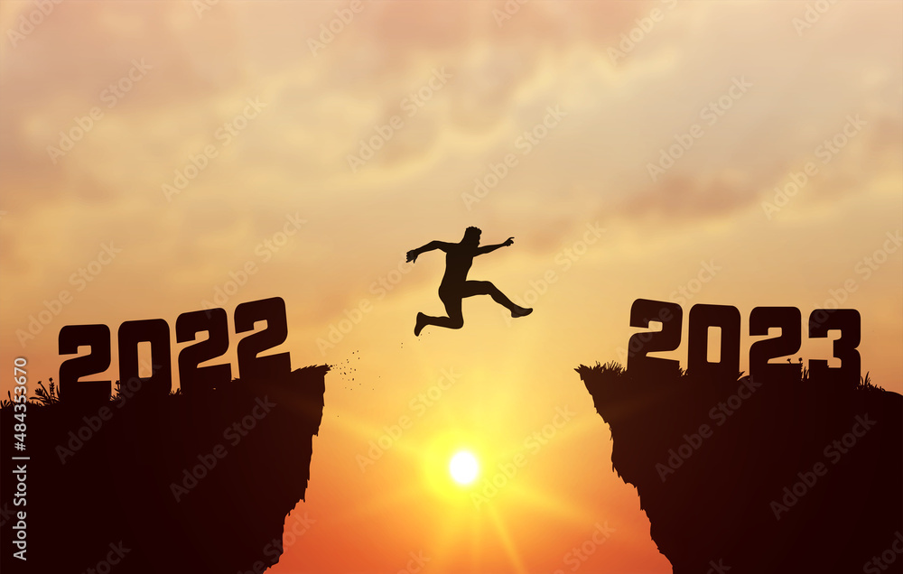 A young silhouette man jump between 2022 and 2023 years over the sun