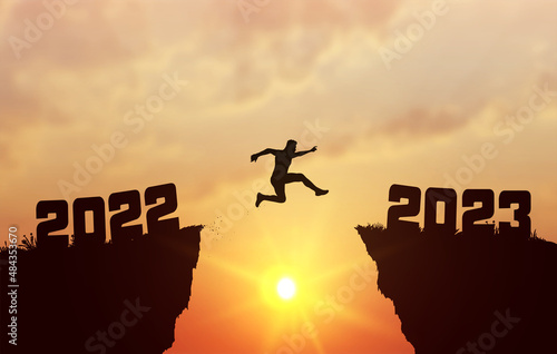 A young silhouette man jump between 2022 and 2023 years over the sun and through on the gap of hill evening sky. Business concept. Welcome Happy New Year 2023. Vector illustration.