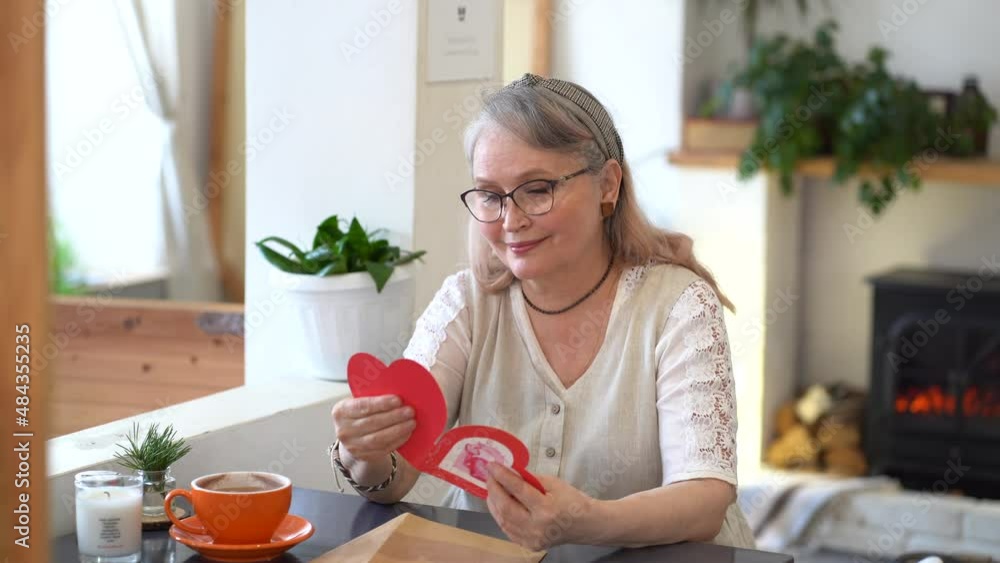Beautiful woman opens a valentine card and smiles Beautiful woman opens a valentine card and smiles