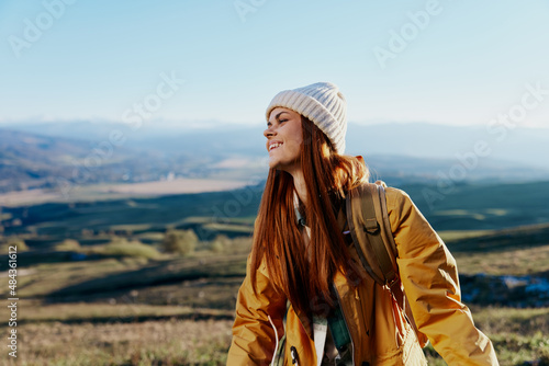 woman in a yellow jacket in a hat backpack travel mountains relaxation
