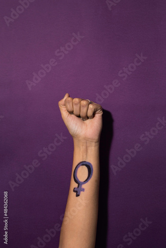 Woman raises her fist with a feminist symbol on her forearm, fights for gender equality, feminism, female power photo