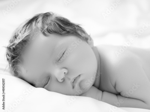 A Baby girl with Smily Face During Sleep. Little baby girl sleeping on white blanket. Beautiful portrait of little child girl 14 days, two weeks old. Motherhood