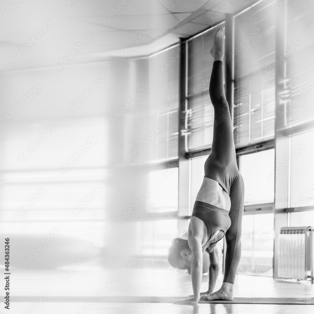 Flexible athletic slim woman in sportswear doing split, monochrome image aspect ratio for social media feed