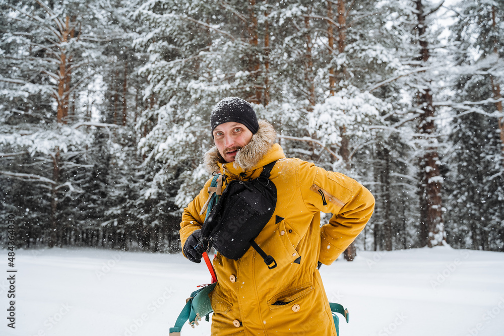 Smiling and happy traveler with belt bag. Snowy forest and rocks. Climbing the mountain in winter. Survival in the wild. Smiling and happy traveler with belt bag. Snowy forest and rocks. Climbing the mountain in winter. Survival in the wild.