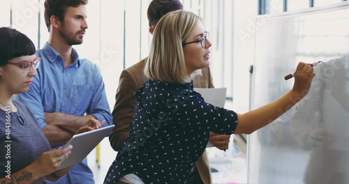 Writing it down for them. Cropped shot of an attractive young businesswoman using a whiteboard while giving an explanation to her colleagues.