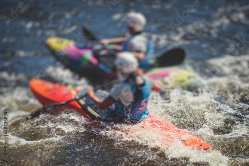 Kayak slalom canoe race in white water rapid river, process of kayaking competition with multiple colorful canoe kayak boat paddling, process of canoeing with big water splash photo