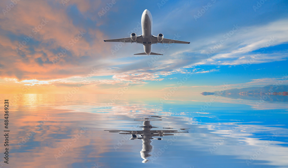 Naklejka premium Airplane flying over tropical sea at sunset