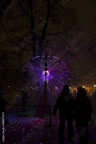Vilnius, Lithuania - January 28, 2022: Disco ball reflects Lazer lights in Park at Vilnius Light Festival. Popular colorful light installation at celebration at night. The explosion of the universe 