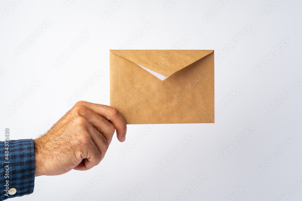 Male hand holding small envelope against the white surface Male hand holding small envelope against the white surface