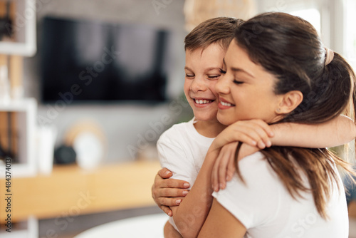 Kind caucasian boy, making his mother happy, on mother's day, by hugging her.