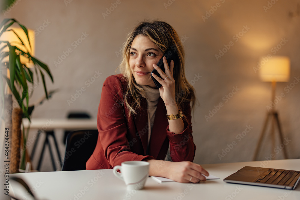 Smiling ambitious woman, having a phone call, while working over the laptop. Smiling ambitious woman, having a phone call, while working over the laptop.