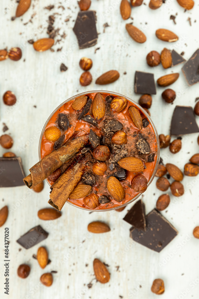 Fototapeta premium Smoothie or pudding with chocolate, hazelnuts and almonds served in a bowl for breakfast. Flat lay image
