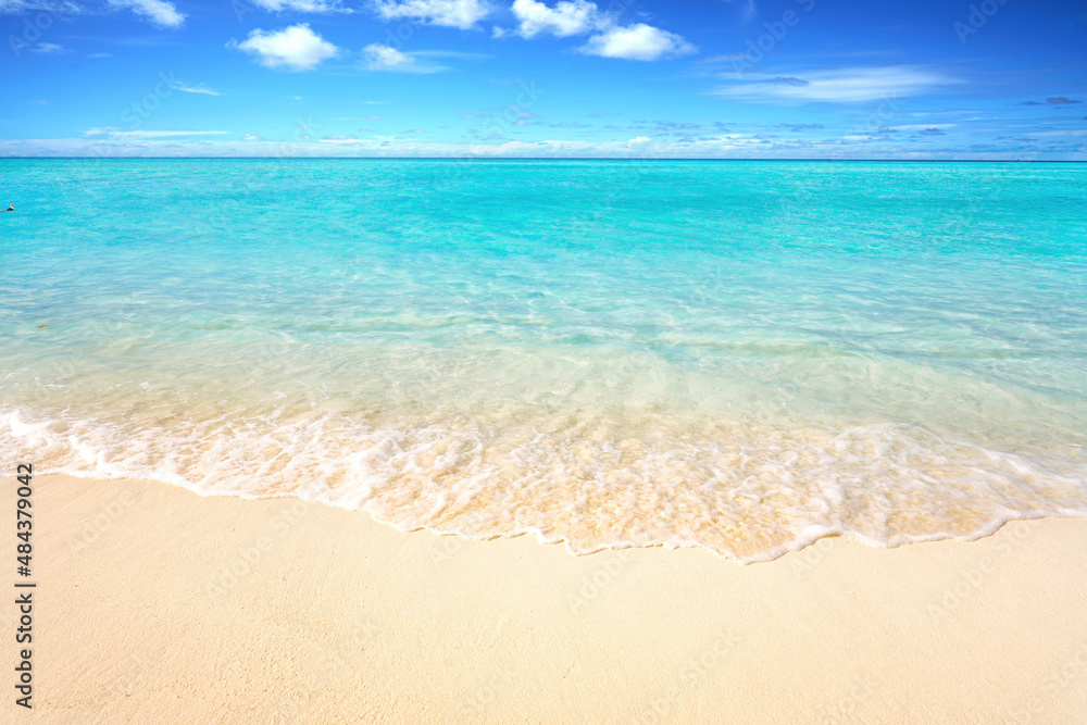 Beautiful sandy beach with white sand and rolling calm wave of turquoise ocean on Sunny day. White clouds in blue sky. Perfect tropical seascape, copy space.