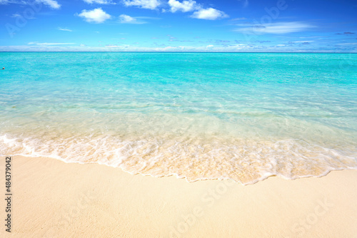 Beautiful sandy beach with white sand and rolling calm wave of turquoise ocean on Sunny day. White clouds in blue sky. Perfect tropical seascape  copy space.