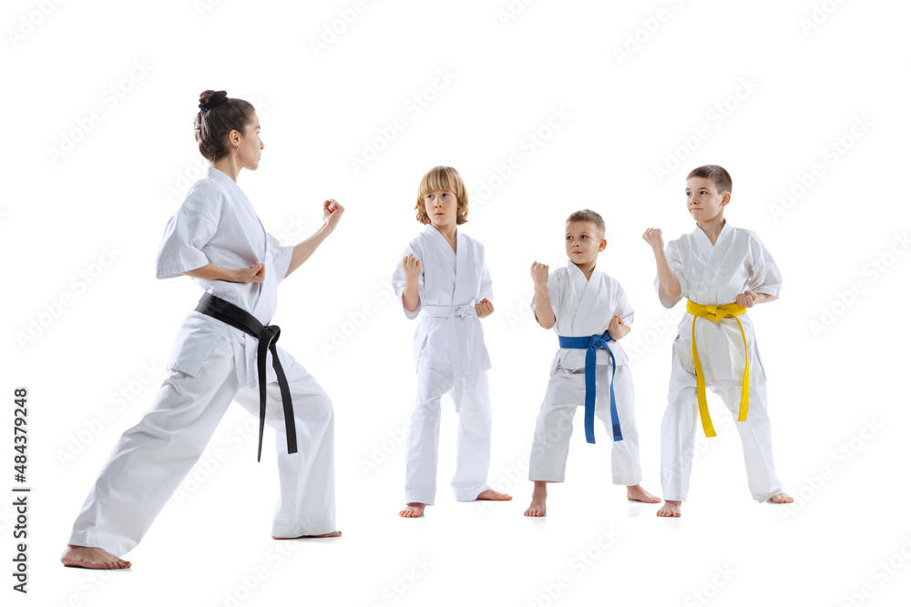 Group of kids, boys, taekwondo athletes wearing doboks training with master isolated on white background. Concept of sport, martial arts Group of kids, boys, taekwondo athletes wearing doboks training with master isolated on white background. Concept of sport, martial arts