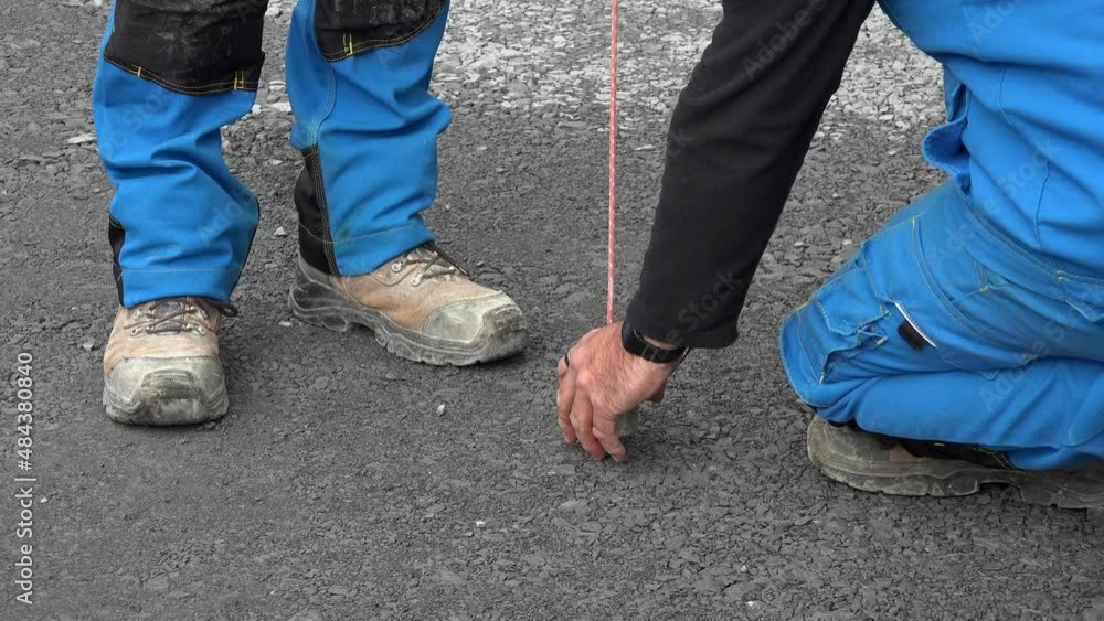 Worker marks a spot on asphalt with florescent spray paint with a plumb line adjustment, High quality 4k footage Worker marks a spot on asphalt with florescent spray paint with a plumb line adjustment, High quality 4k footage