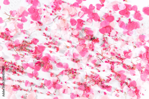 Valentine day or wedding background with paper pink hearts and rose flowers confetti, a flat lay on a white background