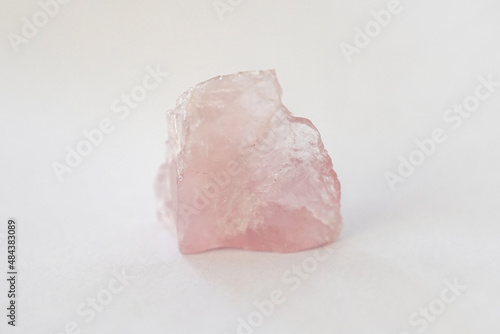 macro shooting of raw Rose quartz stone isolated on white background. There is noise and grain caused by the texture of stone.
