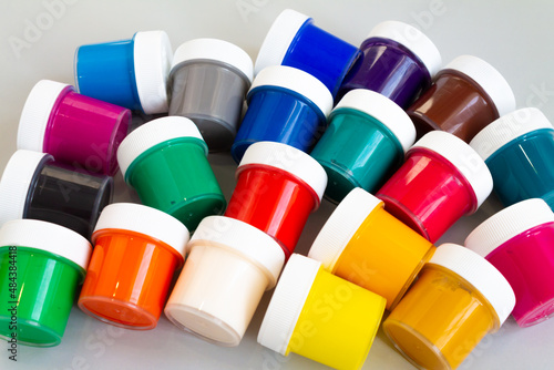 A set of closed jars with gouache of different colors on a gray background. 