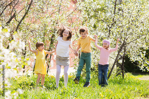 kids friends spend time together in nature. group of children of friends plays in a flowering garden 