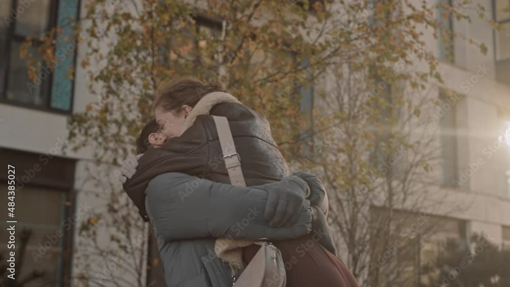 Medium slowmo shot of happy young Caucasian couple meeting outdoors on sunny autumn day Medium slowmo shot of happy young Caucasian couple meeting outdoors on sunny autumn day