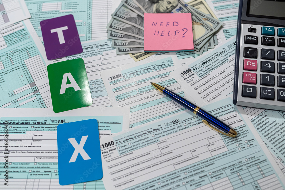 many American tax forms 1040 lie mixed with a piece of paper from a notebook on them many American tax forms 1040 lie mixed with a piece of paper from a notebook on them