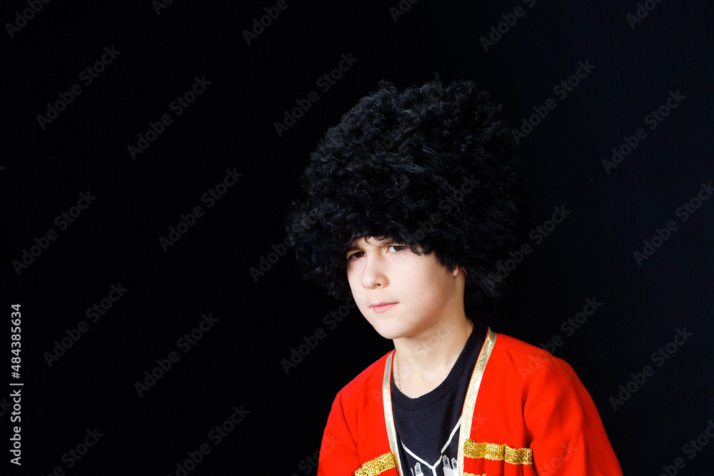 A boy in a national Caucasian outfit on a black background. Traditions and customs of the Eastern peoples. A boy in a national Caucasian outfit on a black background. Traditions and customs of the Eastern peoples.