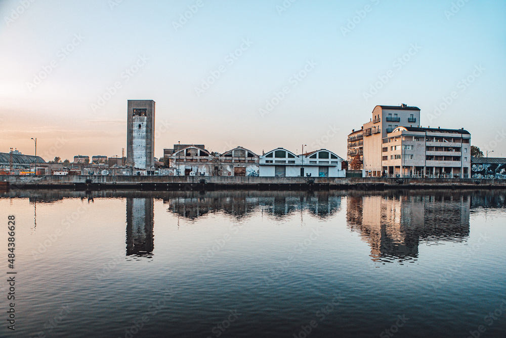 Line of buildings by river with reflections.
