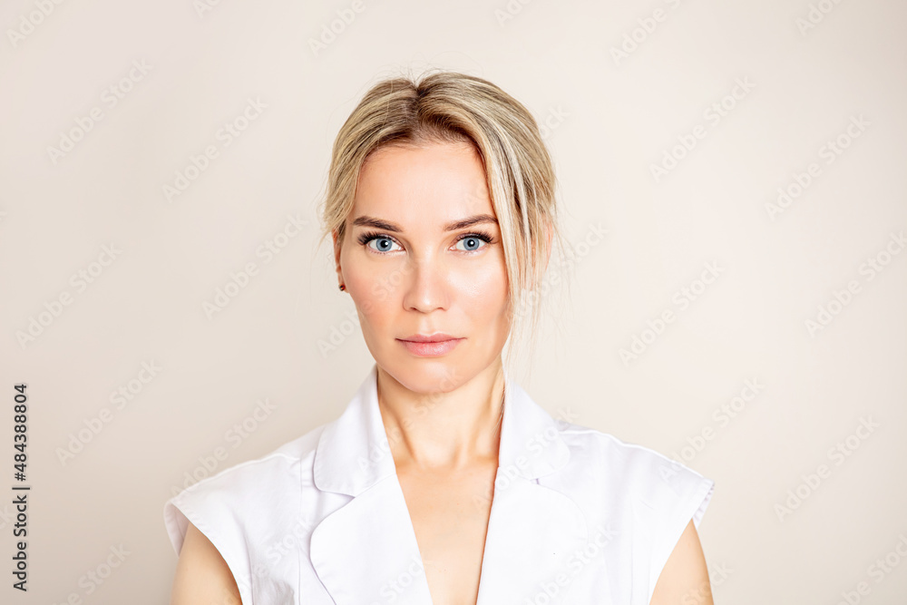 Portrait of a beautiful blonde woman with blue eyes on a light background, looking straight
