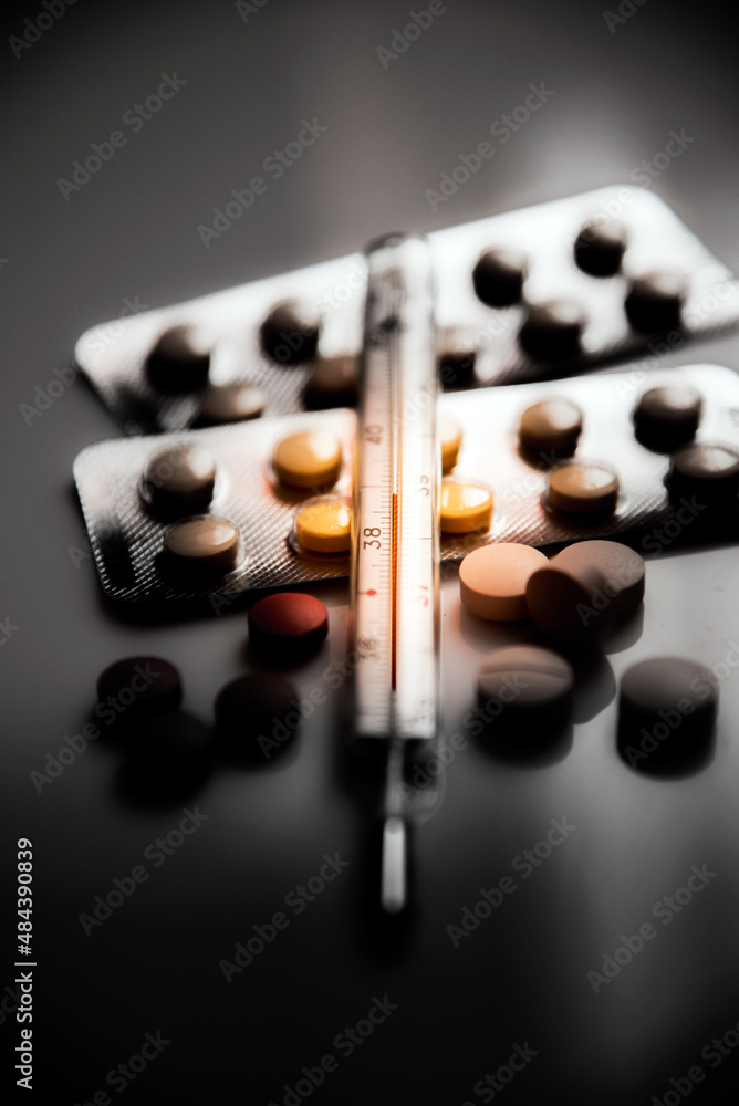 Abstract dark pessimistic image of a thermometer with high temperature and medication (Сovid - concept).