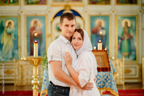 man and woman in headscarf and light-colored robes in church. 