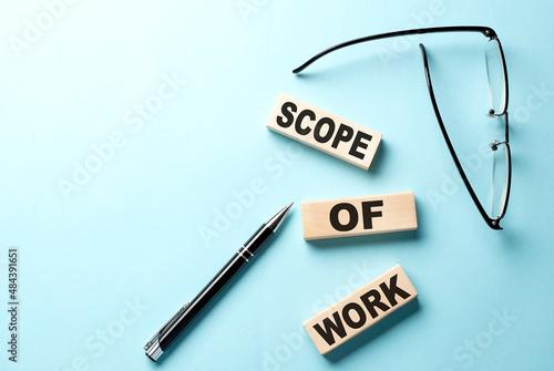 Text SCOPE OF WORK concept on wooden block on the blue background photo