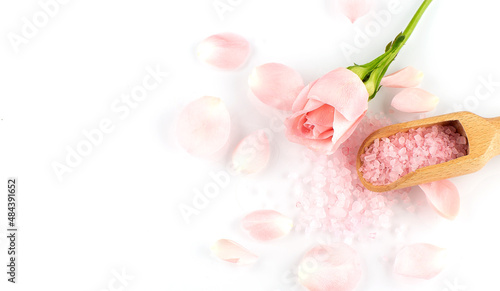 Roses petals and wooden spoon on pink salt, copy space
