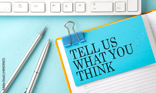 Картината върху платно TELL US WHAT YOU THINK text on sticker on the blue background with pen and keybo