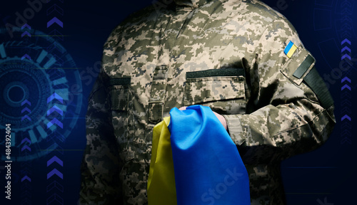 soldier of the Ukrainian armed forces stands with a blue-yellow flag of Ukraine on a black background. Honoring veterans and commemorating those killed in the war