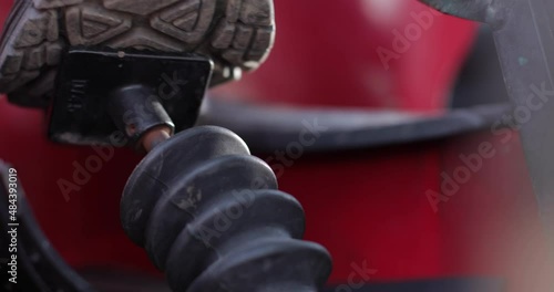 A man presses the pedal of an agricultural machine, close-up of male feet in boots. photo