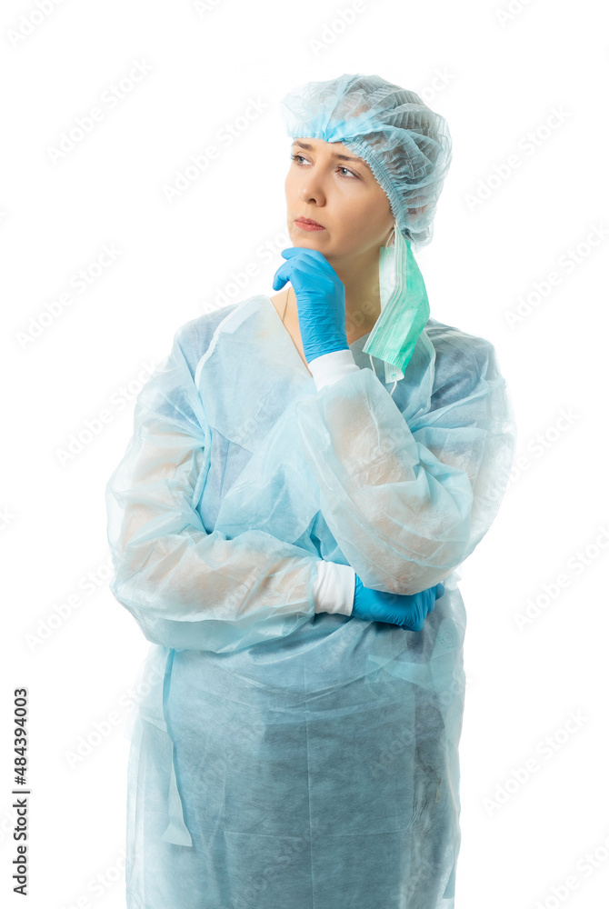 A nurse in sterile disposable clothes and a mask is standing thinking. the doctor recalls this. isolated A nurse in sterile disposable clothes and a mask is standing thinking. the doctor recalls this. isolated