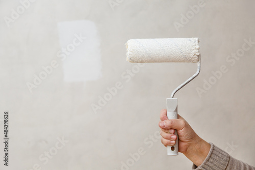 Painting roller in worker's hand. Repair in a room. Painting of walls