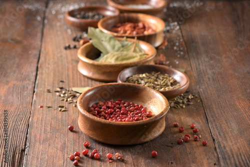 Various spices in a row of wooden bowls on rustic dark planks  copy space  selected focus