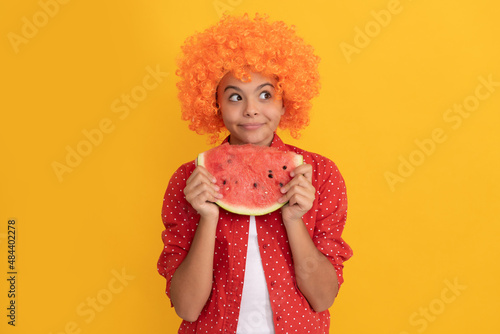 happy child in fancy orange hair wig hold fresh ripe water melon slice fruit, organic food