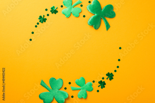 Top view photo of st patricks day circle composition green shamrocks and confetti on isolated yellow background with empty space