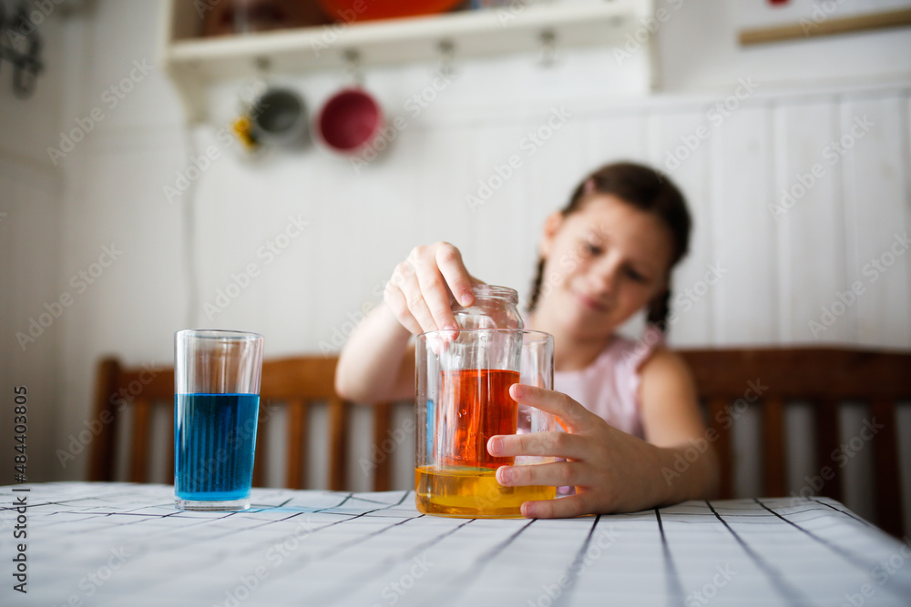 Caucasian kid girl play in the kitchen at home with colored liquids. Experiments with color at home. Caucasian kid girl play in the kitchen at home with colored liquids. Experiments with color at home.