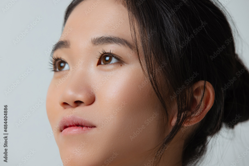 Close-up portrait of dreamy, beautiful girl looking away, posing isolated over gray studio background Close-up portrait of dreamy, beautiful girl looking away, posing isolated over gray studio background