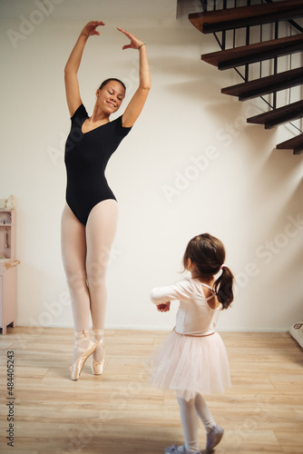 Young mother and 3 years old daughter dancing classical ballet at home