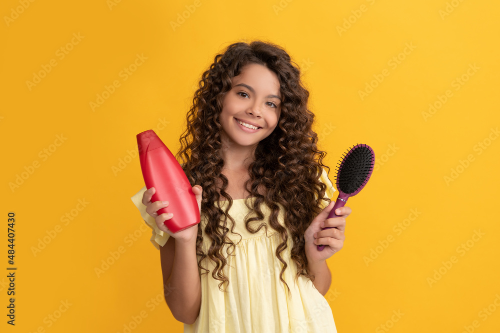happy child with long curly hair hold shampoo bottle and hairbrush, hair happy child with long curly hair hold shampoo bottle and hairbrush, hair