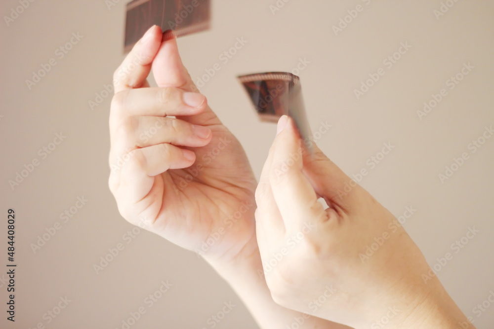 A woman's hand holding a 35 mm film and shining in the light outside the room. A woman's hand holding a 35 mm film and shining in the light outside the room.