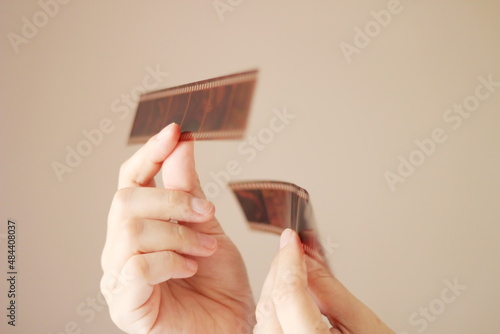 A woman's hand holding a 35 mm film and shining in the light outside the room.