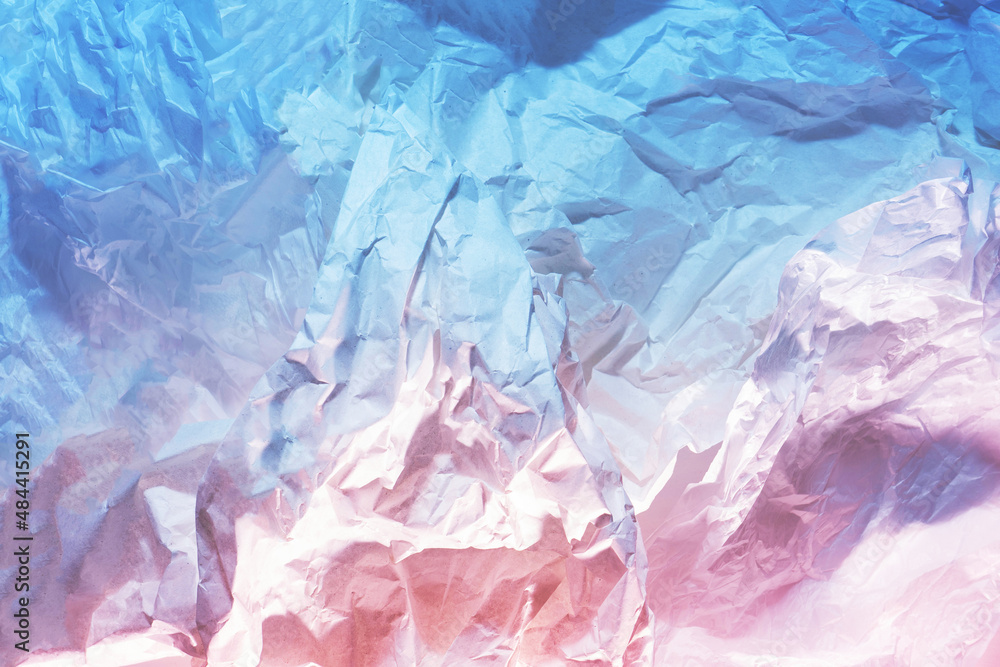 Crumpled white paper texture enlightened with two colored lights pink and blue. Flat lay.