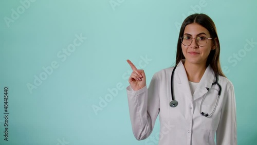 Caucasian Smiling Female Doctor Wear White Uniform And Stethoscope Pointing On Copyspace Isolated Over Blue Background In Studio, Place For Text Or Image, Showing Empty Space For Mock Up