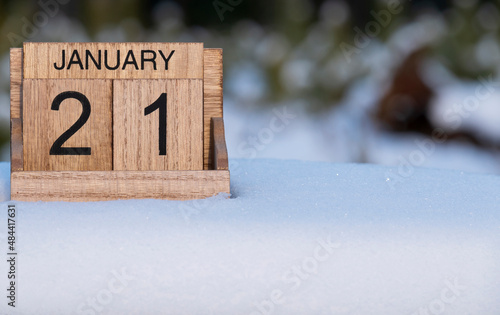 Wooden calendar of January 21 date standing in the snow in nature.